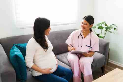 Female doctor and expectant mother laughing during a check-up